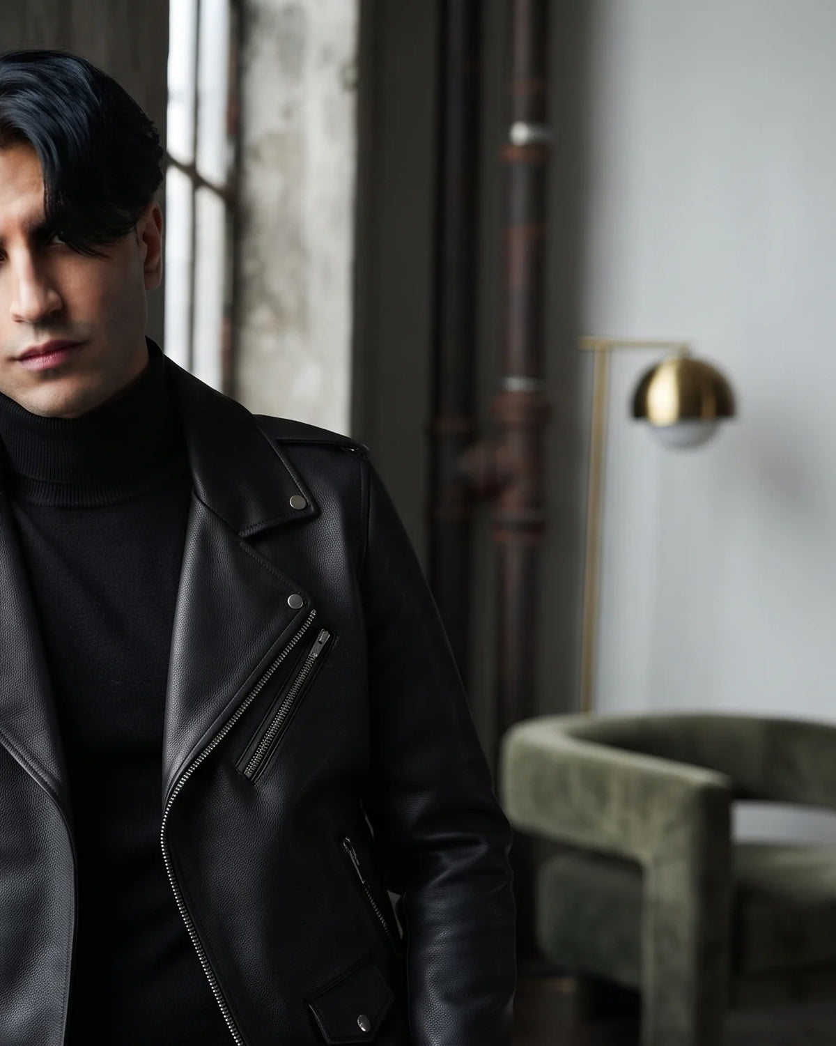 Zaryash black faux leather biker jacket, leaning by a window